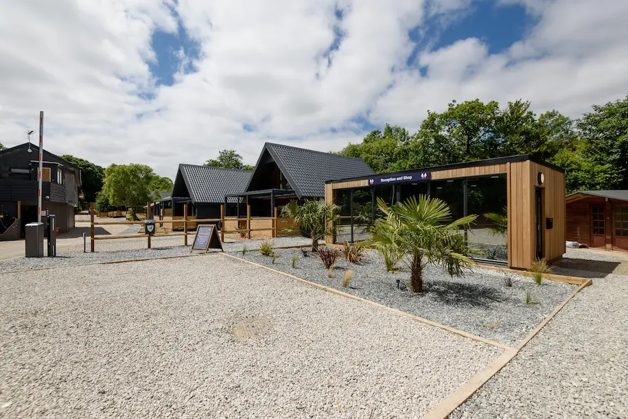 Modern holiday park reception and shop building at Ohana Mua, surrounded by landscaped grounds.