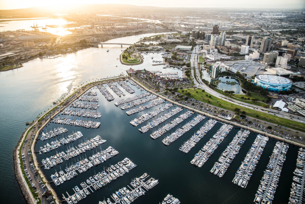 Aerial view of a large marina filled with yachts and boats, with city skyline and harbour in the background.